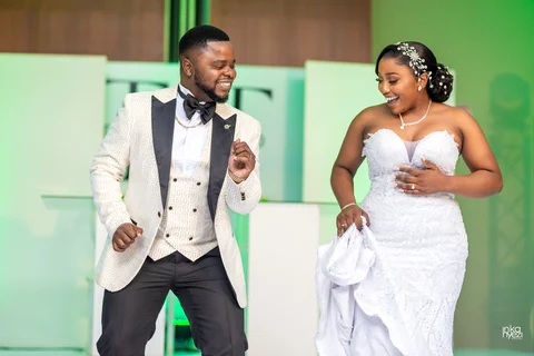A bride and groom laughing and dancing together on their wedding day